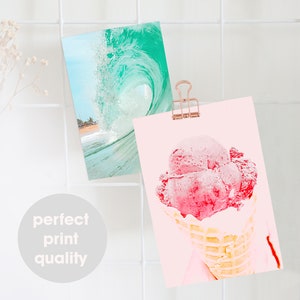 May include: Two prints, one with a turquoise wave crashing on a beach and the other with a pink ice cream cone on a light pink background.