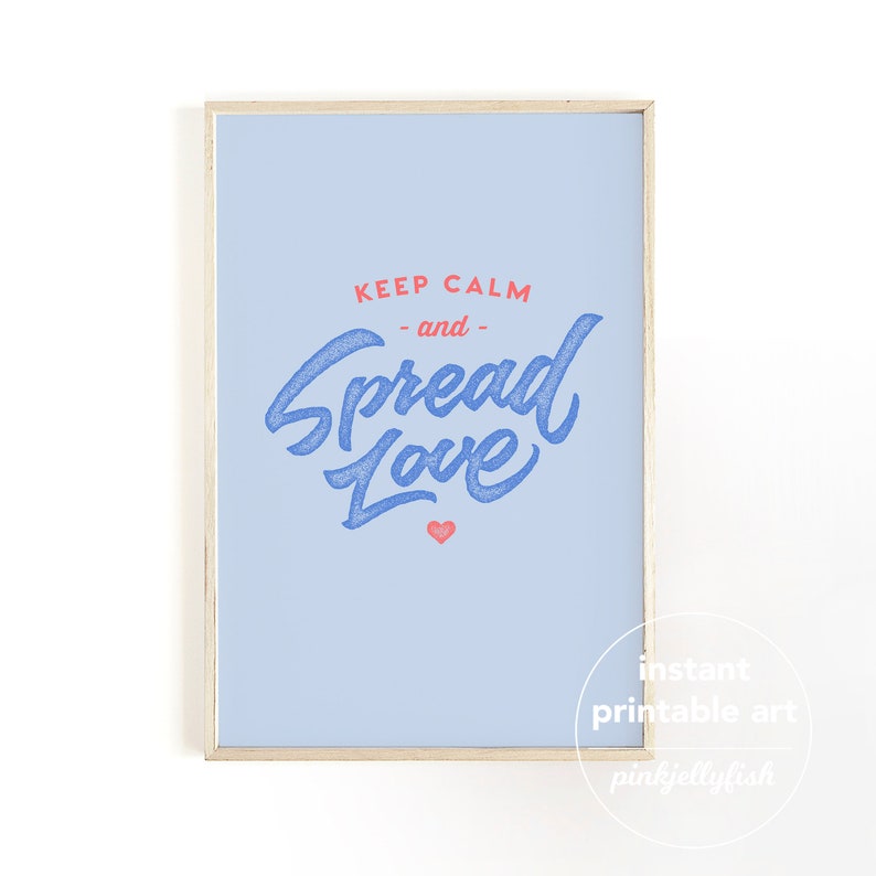 May include: A framed print with a pale blue background. The text "KEEP CALM - and - Spread Love" is written in blue script with a red heart. The frame is a light wood colour. The words "instant printable art" and "pinkjellyfish" are in the bottom right corner.