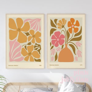 May include: Two framed prints with a botanical theme. The prints feature stylised flowers in shades of orange, pink, and brown. The text "Botanical collection" and the years "1980" and "1975" are printed below the images.
