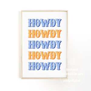 May include: A framed print featuring the word "HOWDY" in a repeating pattern of blue and orange. The text is in a bold, vintage style, set against a white background. The frame is a light wood color.