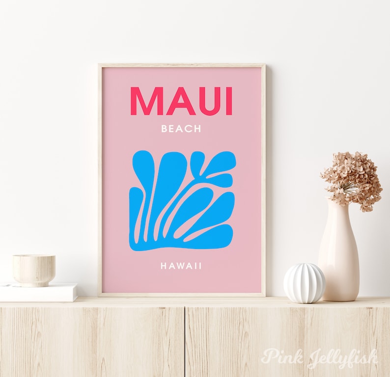 May include: A pink and white poster with the text "MAUI BEACH HAWAII" in bold red and white lettering. A blue stylized floral design is in the center of the poster.