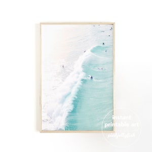 May include: An aerial view of a turquoise ocean with white waves crashing. Several people are surfing in the water.