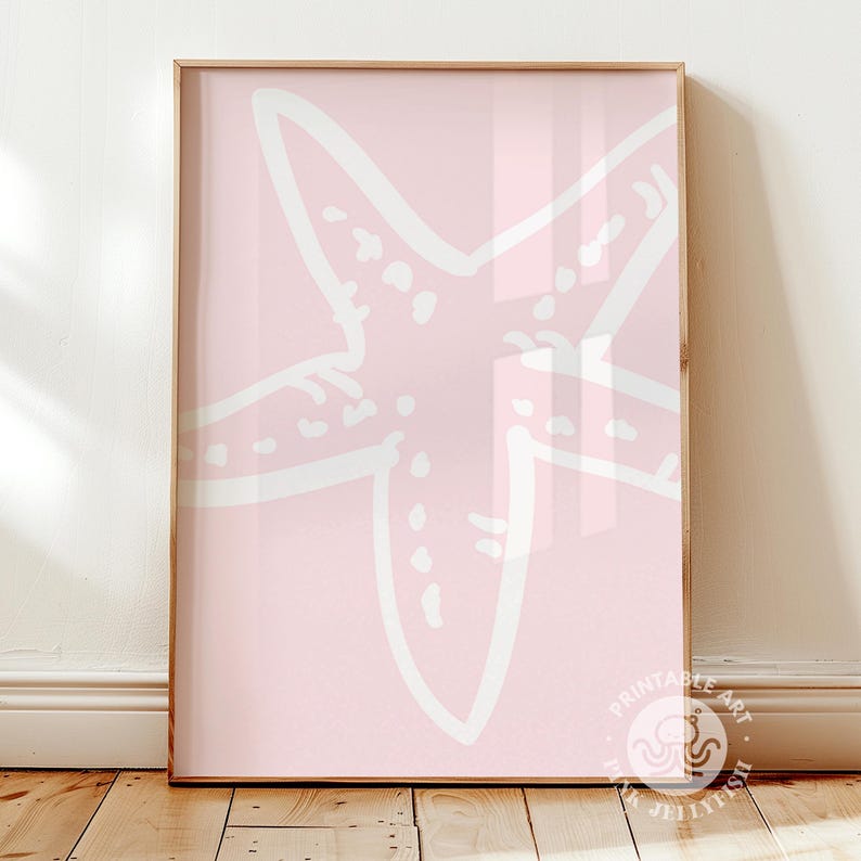 Puede incluir: Una impresi&oacute;n enmarcada con un dise&ntilde;o de estrella de mar blanca sobre un fondo rosa p&aacute;lido. La estrella de mar est&aacute; delineada con l&iacute;neas gruesas e irregulares, y la impresi&oacute;n se muestra en un marco de madera de color claro. La obra de arte es una pieza decorativa.