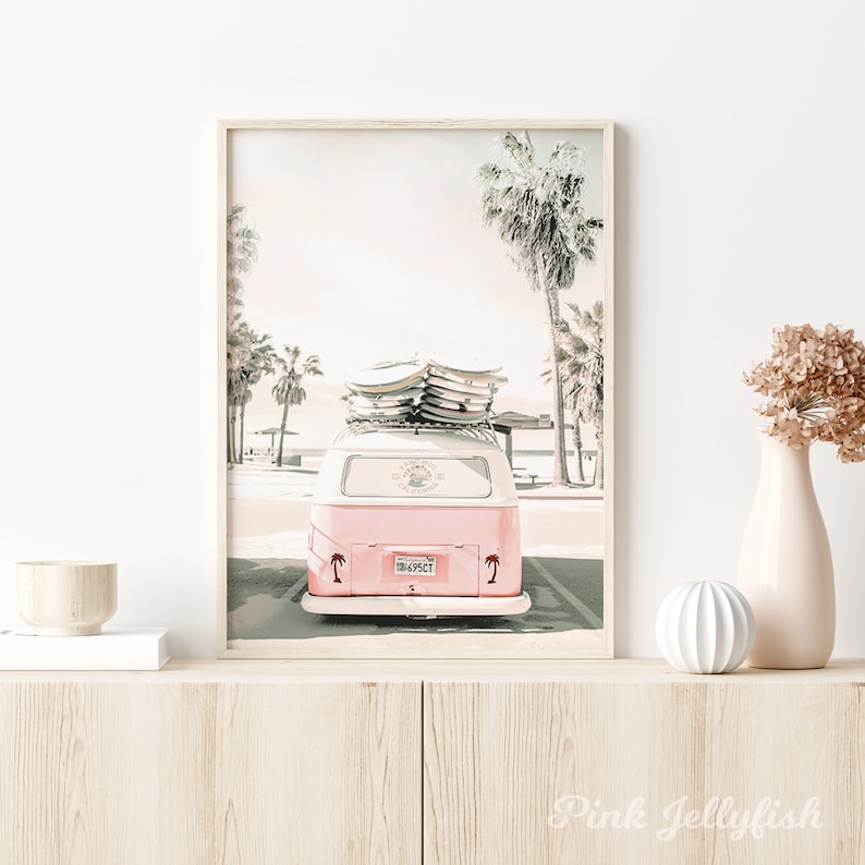 May include: A pink vintage van with surfboards on top, parked in front of palm trees. The van has a license plate that reads "1849SCT".
