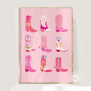 May include: A framed print featuring nine colorful cowboy boots in shades of pink, red, and white. The boots have various designs, including floral patterns and cacti, set against a light pink background. The artwork is in a vertical orientation.