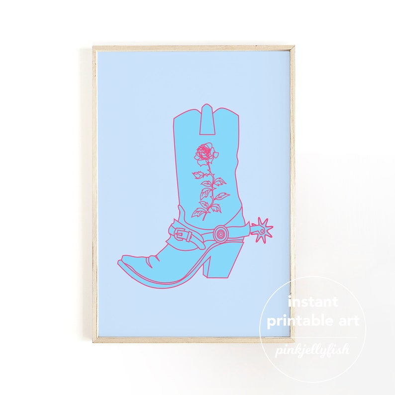 May include: A framed print showing a light blue cowboy boot with a pink rose design and spur on a light blue background. The words "instant printable art" and "pinkjellyfish" are in the lower right corner.