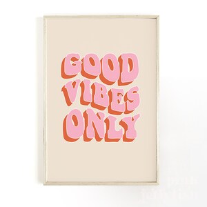 May include: A beige framed print with the text "GOOD VIBES ONLY" in pink and orange letters.