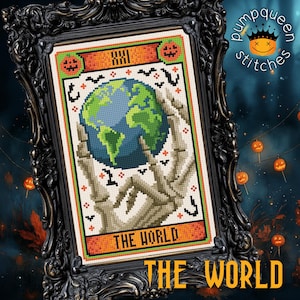 May include: A framed cross-stitch of "The World" tarot card, featuring a blue and green globe held by skeletal hands. The design includes orange and green accents, with the text "XXI" and "THE WORLD". The frame is ornate and black.