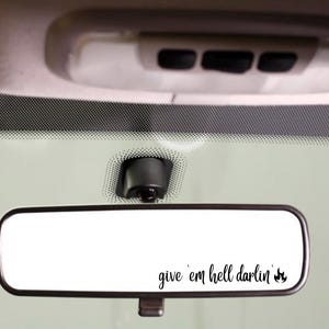May include: A rearview mirror with the text "give 'em hell darlin'" and a small flame graphic.