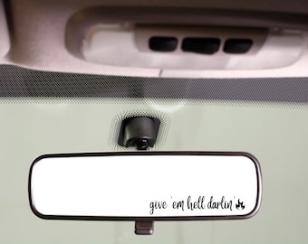 May include: A rearview mirror with the text "give 'em hell darlin'" and a small flame graphic.