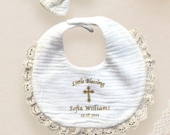 May include: White baby bib with a lace trim and embroidered cross, text reads "Little Blessing Sofia Williams 12 05 2025".