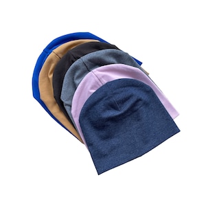 May include: A stack of six beanies in various colors, including blue, brown, black, gray, pink, and denim.