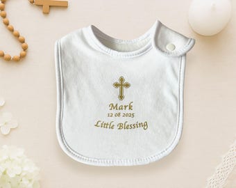 May include: White baby bib with a gold cross and the text "Mark 12 08 2025 Little Blessing".