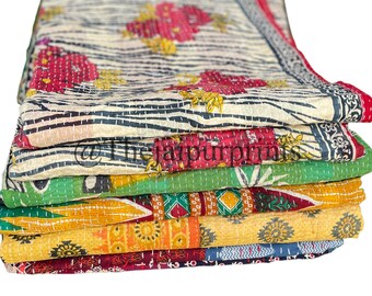 May include: A stack of colorful kantha quilts with various floral and geometric patterns. The quilts are folded and stacked on top of each other, creating a visually appealing display.