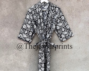 May include: Black and white floral print robe with a long sleeve and a tie belt. The robe is hanging on a white hanger against a gray wall. The text "@TheJungalowPrints" is visible in the bottom left corner of the image.