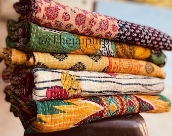 May include: A stack of six colorful kantha quilts with various patterns and designs. The quilts are folded and stacked on top of each other, creating a visually appealing display. The quilts are made of cotton and are hand-stitched.