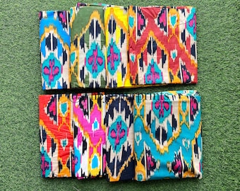 Könnte beinhalten: Acht Stoffmuster mit einem farbenfrohen Ikat-Muster. Die Muster sind in zwei Reihen zu je vier angeordnet. Die Farben umfassen Rot, Orange, Gelb, Grün, Blau, Schwarz und Weiß.
