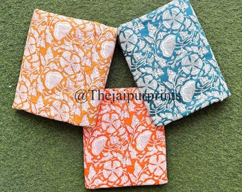 May include: Three fabric squares with a white floral pattern on a green background. The squares are orange, teal, and a lighter shade of orange. The text "@Thejaipurprints" is visible on the teal square.