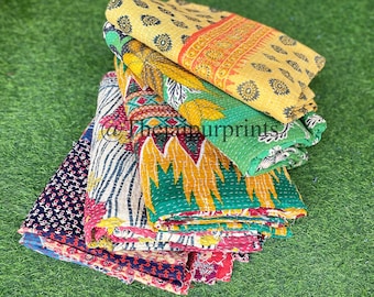 May include: A stack of colorful kantha quilts with various patterns, including floral, geometric, and paisley designs. The quilts are made of recycled saris and are perfect for adding a touch of bohemian style to any room.