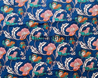 May include: Blue fabric with a repeating pattern of pink flowers with white centres and orange accents. The flowers are surrounded by green and white leaves.
