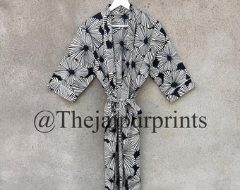 May include: A black and white floral print robe with a long sleeve and a tie belt. The robe is hanging on a white hanger against a gray wall. The text "@Thejaprints" is visible in the bottom left corner of the image.