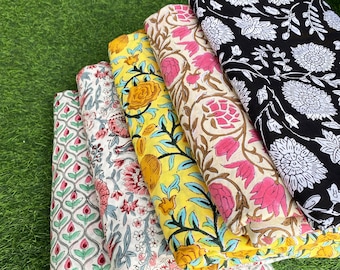 May include: A stack of five fabric squares with different floral patterns. The fabrics are in shades of pink, yellow, white, and black.