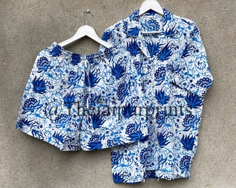 Puede incluir: Un conjunto de pijama blanco y azul con estampado floral. La parte superior tiene cuello y mangas cortas. Los pantalones cortos tienen una cintura elástica.
