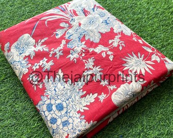 Pode incluir: Tecido vermelho com um padrão floral branco e azul. O tecido está dobrado ao meio e sobre uma superfície verde.