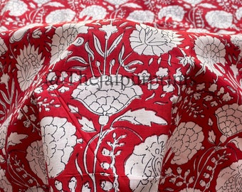 Pode incluir: Tecido vermelho com um padrão floral branco. O tecido está dobrado ao meio, mostrando o padrão em ambos os lados.