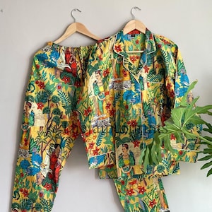 Könnte beinhalten: Ein gelber, grüner und roter Pyjama-Set mit einem floralen und Porträt-Druck. Das Set beinhaltet ein langärmliges Hemd mit Knopfleiste und eine passende Hose.