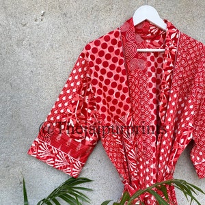 May include: Red cotton robe with a patchwork design featuring various patterns, including polka dots, swirls, and floral motifs. The robe has a tie belt and three-quarter sleeves.
