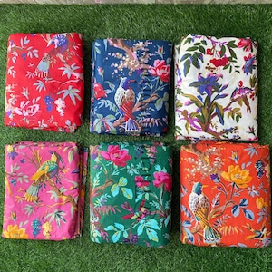 Op de afbeelding: Zes verschillende stofstalen met een bloemen- en vogelprint. De stoffen zijn in rood, roze, blauw, groen, wit en oranje.