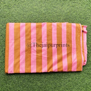 May include: A folded piece of fabric with pink and brown stripes. The fabric has a textured surface and is folded in half. The text "@Thejaipurprints" is printed on the fabric.