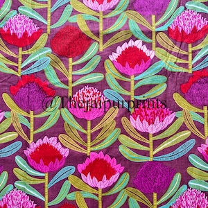 Op de afbeelding: Een textielstof met een herhalend patroon van gestileerde proteabloemen in tinten roze, magenta en donkerrood, tegen een donkerpaarse achtergrond. De bloemen hebben groene stengels en bladeren. De tekst @Thejaipurprints is zichtbaar.
