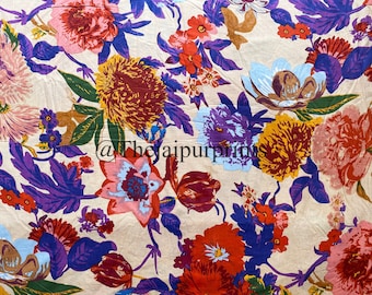 May include: A beige fabric adorned with a colourful floral design. The pattern showcases large flowers in pink, red, yellow, and purple, with green leaves and blue accents. The text "@thejaipurprints" is visible.