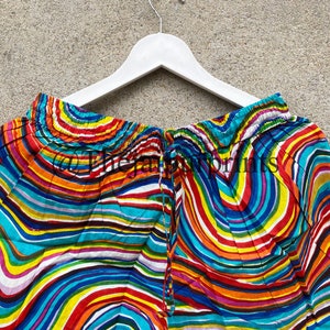 May include: A pair of colorful shorts with a wavy, striped pattern in shades of blue, red, yellow, green, and purple. The shorts have a drawstring waist and a white trim.