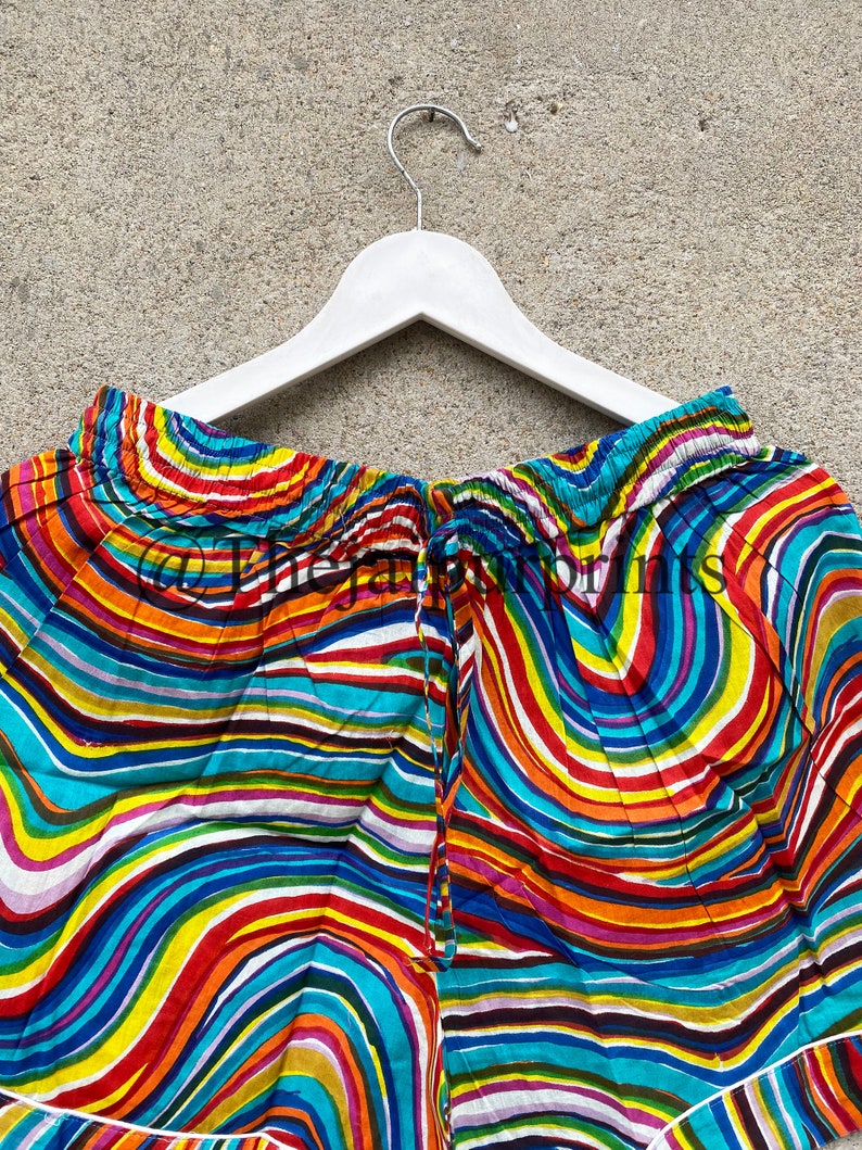 May include: A pair of colorful shorts with a wavy, striped pattern in shades of blue, red, yellow, green, and purple. The shorts have a drawstring waist and a white trim.