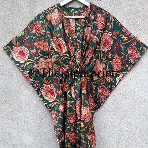 May include: A green cotton kaftan with a floral print in shades of red, orange, and yellow. The kaftan has a V-neck and a tie at the waist.