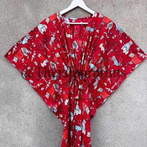 May include: Red kaftan with a white and blue print of animals and trees. The kaftan has a V-neck and a tie at the waist.