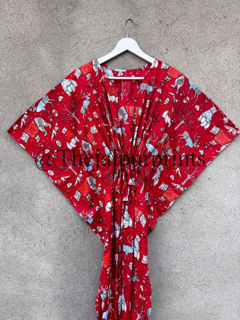 May include: Red kaftan with a white and blue print of animals and trees. The kaftan has a V-neck and a tie at the waist.