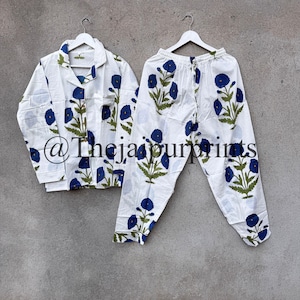 May include: White pajama set with a blue floral pattern. The set includes a button-down shirt with a chest pocket and pants with a drawstring waist. The floral design features blue flowers and green leaves. The text "@Thejaipurprints" is visible.