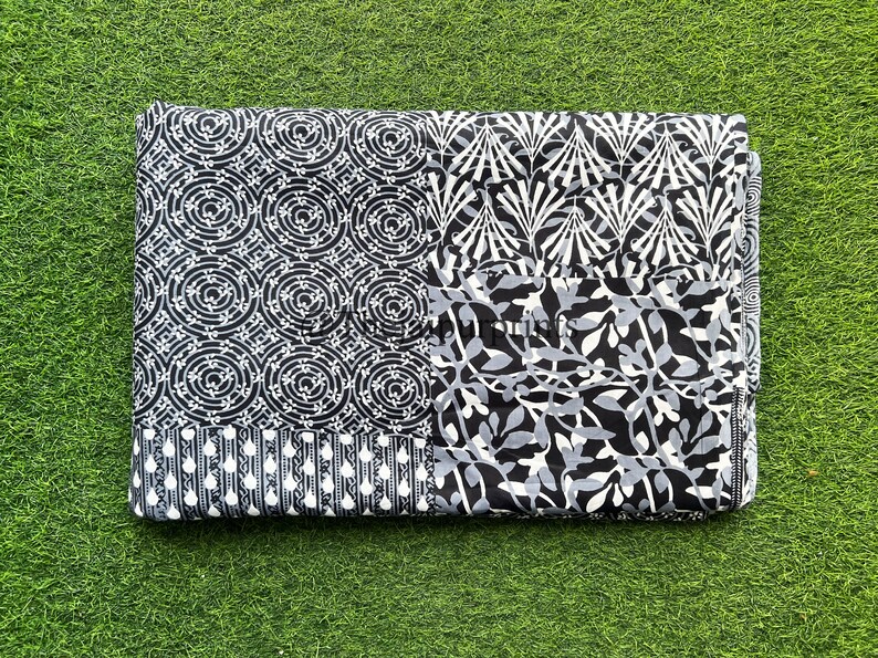 以下が含まれることがあります： 黒と白の綿生地で、パッチワークのデザインが施されています。幾何学模様と花柄が組み合わされています。