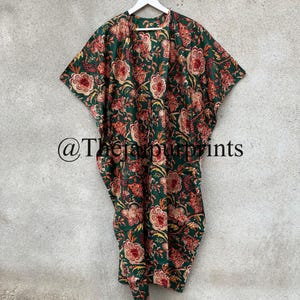 May include: A green kimono with a floral print in shades of orange and white. The kimono is hanging on a white hanger against a gray wall. The text "@TheSimplePrints" is visible in the lower left corner of the image.