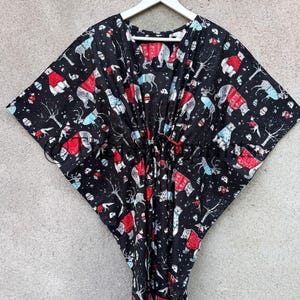 May include: Black kaftan with a white hanger. The kaftan has a red and white print of polar bears wearing red hats and scarves. The print also includes trees, birds, and other wintery elements.