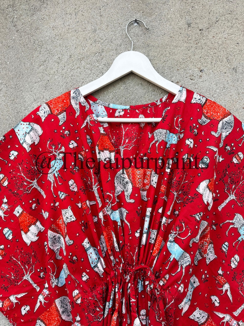 May include: Red cotton kaftan with a drawstring waist and a print of various animals wearing sweaters. The animals include bears, deer, and foxes.