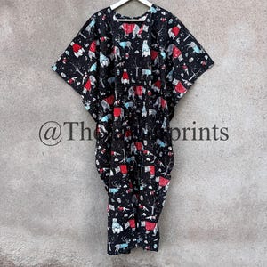 May include: A black kaftan with a white hanger. The kaftan has a colorful print of animals wearing sweaters. The print includes bears, deer, and foxes.