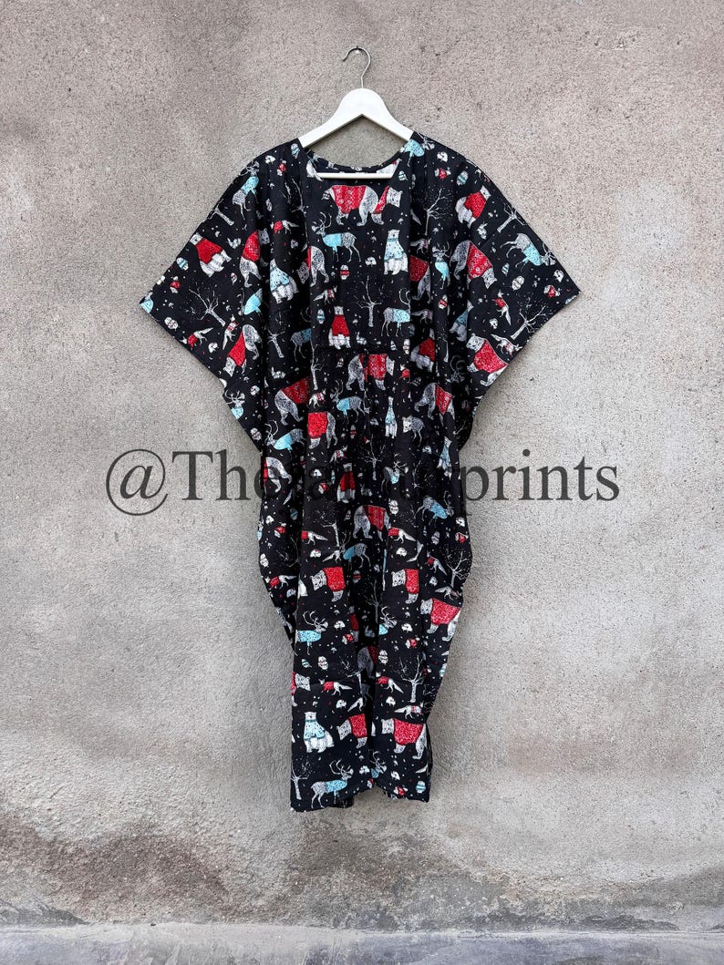 May include: A black kaftan with a white hanger. The kaftan has a colorful print of animals wearing sweaters. The print includes bears, deer, and foxes.