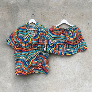 May include: A colorful pajama set with a short-sleeved shirt and shorts. The fabric features a wavy, abstract pattern in shades of blue, red, yellow, and white.