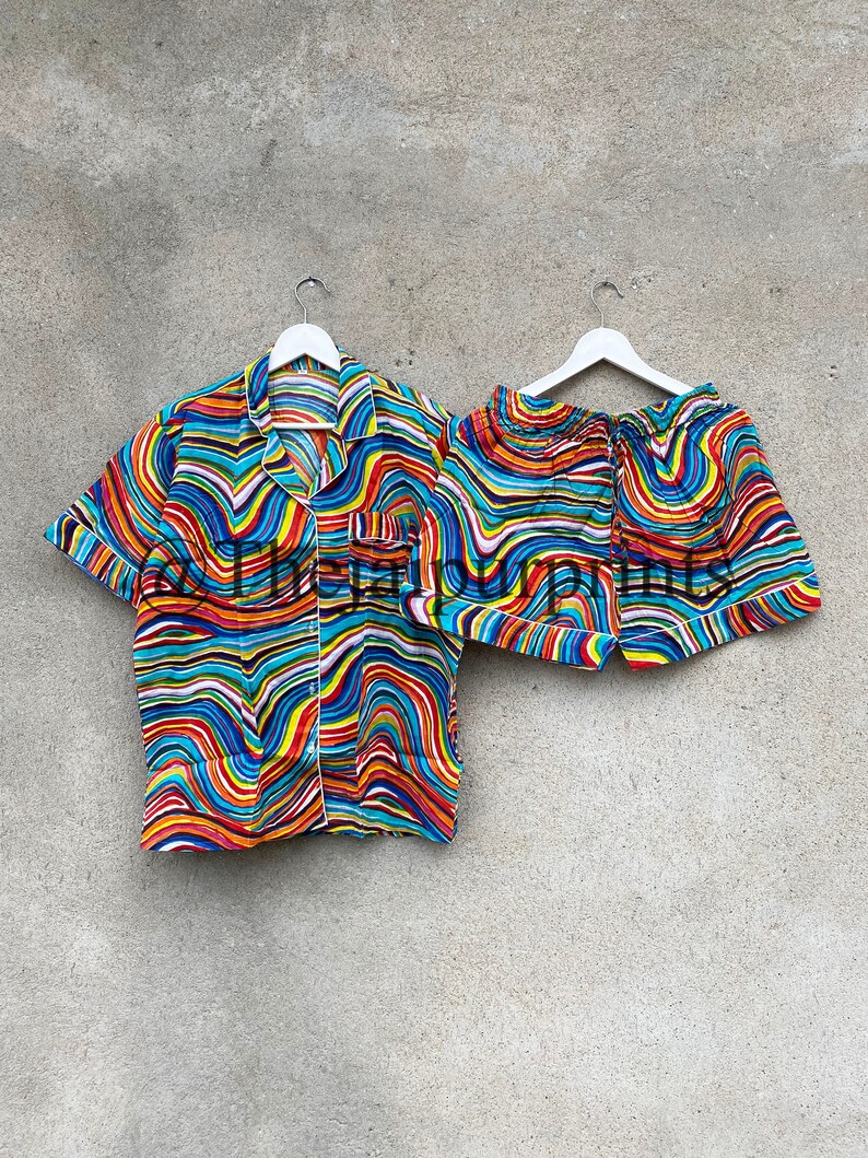 May include: A colorful pajama set with a short-sleeved shirt and shorts. The fabric features a wavy, abstract pattern in shades of blue, red, yellow, and white.