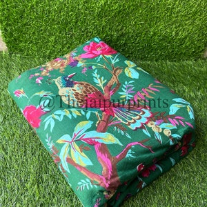 Op de afbeelding: Groene stof met een bloemen- en vogelprint. De stof heeft roze bloemen, groene bladeren en een bruine en blauwe vogel.
